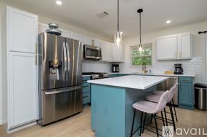 Lake Worth house for rent - A kitchen with a blue island and white cabinets.