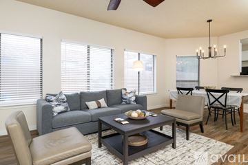 Euless house for rent - A living room with a grey couch, a brown chair, a coffee table, and a dining table with chairs.
