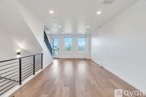 South Jordan townhouse for rent - A spacious room with wooden floors and a staircase with a metal railing.
