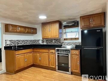 Revere apartment for rent - A kitchen with wooden cabinets and black appliances.