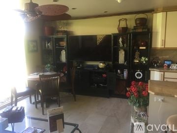 Rancho Mirage condo for rent - A living room with a dining table and chairs, a television, and a cabinet with glass doors.