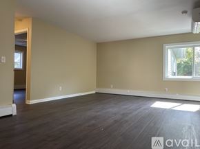 Madison apartment for rent - A spacious room with wooden floors and a window letting in natural light.