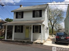Collegeville house for rent - A two-story house with a yellow door and a car parked in front.