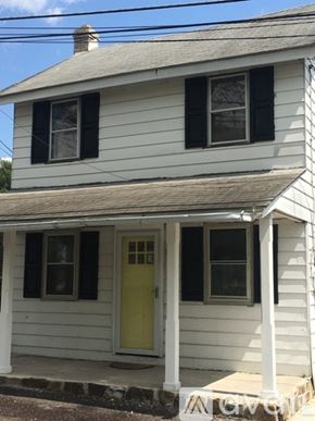 Collegeville house for rent - A small white house with a yellow door and a porch.