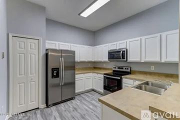 Jacksonville condo for rent - A kitchen with white cabinets and a stainless steel refrigerator.