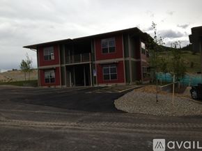 Helena apartment for rent - A red and brown building with a parking lot in front.