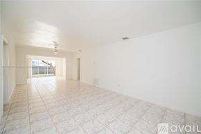 Miami house for rent - A spacious empty room with tiled flooring and white walls.