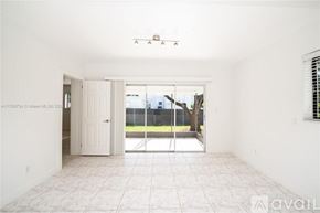 Miami house for rent - A room with a tiled floor and a sliding glass door leading to a backyard.