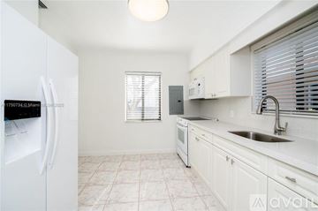 Miami house for rent - A kitchen with white cabinets and a white fridge.