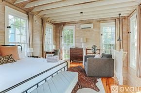 Charlottesville townhouse for rent - A bedroom with a large bed and a grey ottoman.