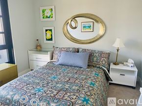Washington condo for rent - A bedroom with a patterned bedspread and a round mirror above it.