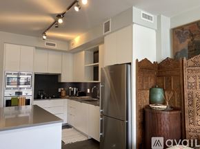 Washington condo for rent - A modern kitchen with white cabinets and a stainless steel refrigerator.