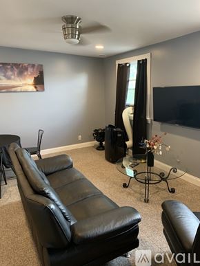 Niagara Falls apartment for rent - A living room with black leather furniture and a painting on the wall.