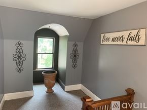 Niagara Falls apartment for rent - A room with a wall decoration that says "love never fails" and a window with a view of trees.