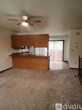 Billings townhouse for rent - A living room with a ceiling fan and a kitchen area in the background.