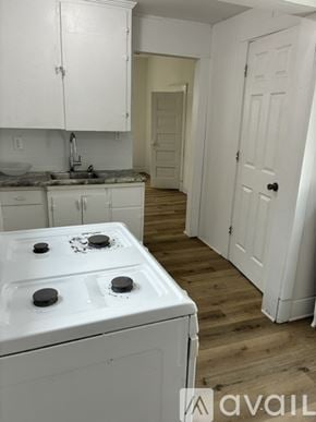 Marshalltown apartment for rent - A white stove top oven with four burners is in a kitchen with white cabinets and a white door.