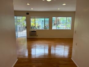 West Hollywood apartment for rent - A room with wooden floors and a window overlooking a patio.