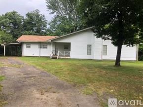 North Little Rock house for rent - A white house with a brown roof and a tree in front.