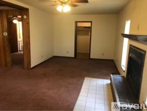 North Little Rock house for rent - A living room with a fireplace and a ceiling fan.