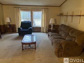 Port Austin house for rent - A living room with a blue chair, brown couch, and a coffee table.