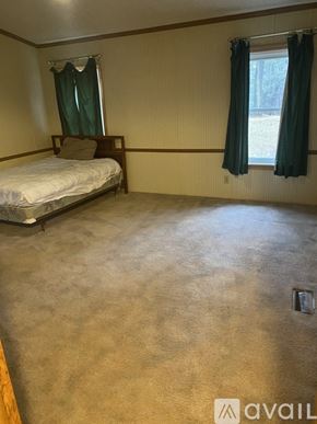 Port Austin house for rent - A bedroom with a bed, window, and carpeted floor.