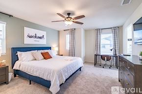 Fresno house for rent - A bedroom with a large bed, a ceiling fan, and a chair.
