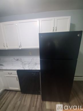La Crosse apartment for rent - A black fridge in a kitchen with white cabinets.