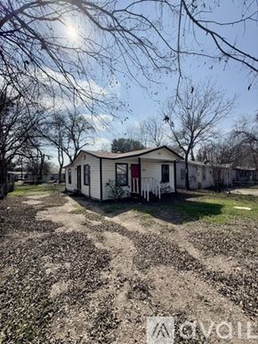 San Antonio house for rent - A small white house with a red door is surrounded by a field of cotton plants.