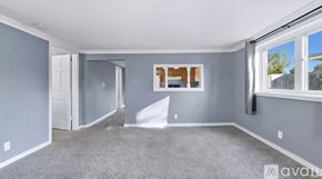 New Haven house for rent - A spacious room with grey walls and carpet flooring, featuring a large window with a view of the outdoors.