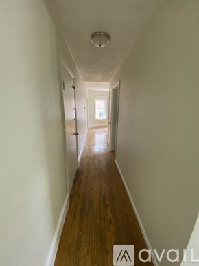 Boston apartment for rent - A long hallway with wooden floors and white walls.