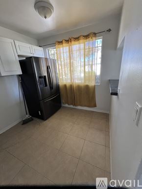 Los Angeles apartment for rent - A kitchen with a black fridge and a window with curtains.