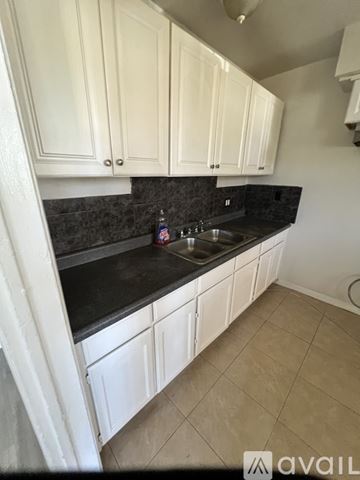 Los Angeles apartment for rent - A kitchen with white cabinets and a black countertop.