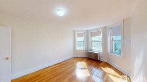 Boston apartment for rent - A room with wooden floors and three windows.