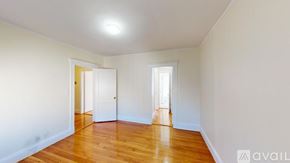 Boston apartment for rent - A room with wooden floors and white walls with two doors.