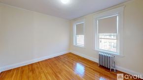 Boston apartment for rent - A room with wooden floors and a window with a view of a building outside.
