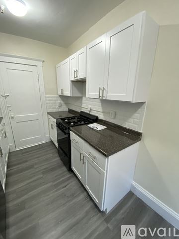 Boston apartment for rent - A kitchen with white cabinets and a black countertop.