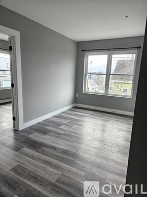 Everett apartment for rent - A room with grey walls and wooden flooring with a window showing a view of a house and trees.