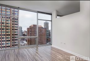 Chicago apartment for rent - A bedroom with a large bed and a grey couch.