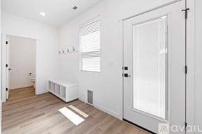 Caldwell house for rent - A room with a white door, window with blinds, and a white bench.