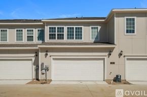Denton townhouse for rent - A house with a beige facade and white garage doors.