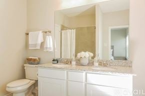 Denton townhouse for rent - A white bathroom with a toilet, sink, and mirror.