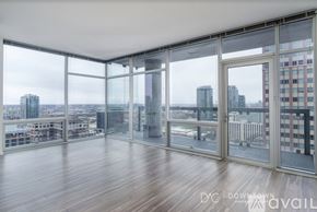 Chicago apartment for rent - A spacious room with wooden floors and large windows overlooking a cityscape.
