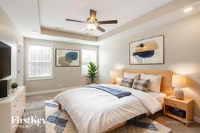 Clarksville house for rent - A bedroom with a bed, a ceiling fan, and a plant.