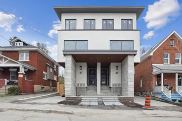 Ottawa apartment for rent - A modern house with a white facade is in front of older brick houses.