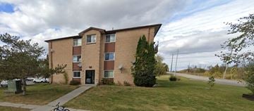 Napanee apartment for rent - A brown brick apartment building with a green lawn in front.
