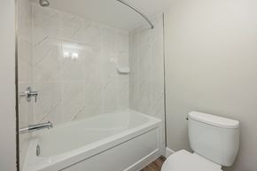 London apartment for rent - A white toilet sits next to a bathtub in a bathroom.