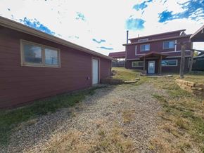La Veta house for rent - A red building with a gravel pathway leading to a white door.