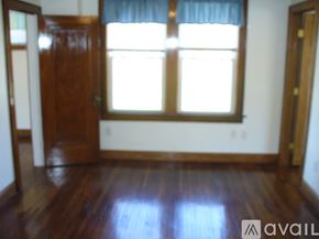 Columbus apartment for rent - A room with a wooden floor and a window with a blue curtain.