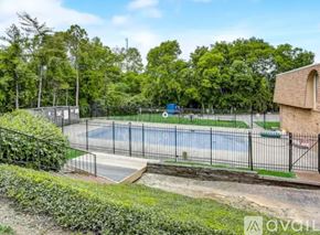 Nashville condo for rent - A tennis court surrounded by a fence and greenery.