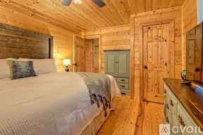 Clayton house for rent - A bedroom with wooden walls and a bed with a white comforter.